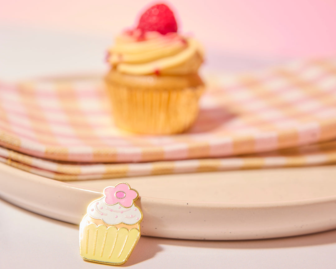 Cupcake-shaped pin with pink flower on a pink background