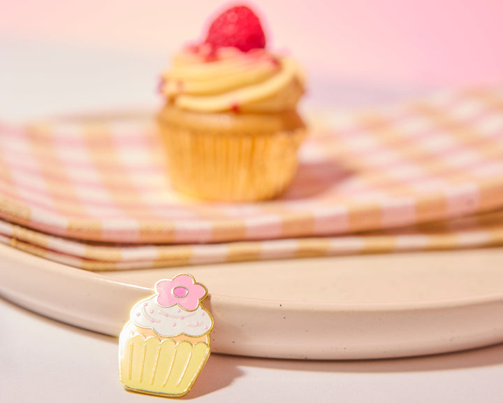 Cupcake-shaped pin with pink flower on a pink background