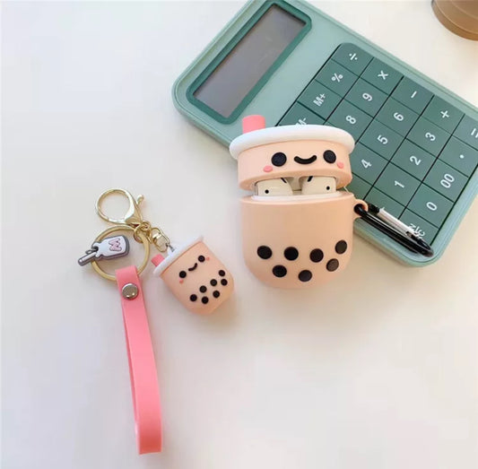 Coral and Ink's Boba keychain lying next to a bubble milk tea air pods case that is lying on a green calculator