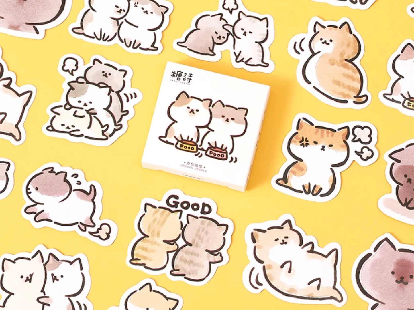 a yellow background with cat stickers laid on top and the cat sticker box placed in the middle 