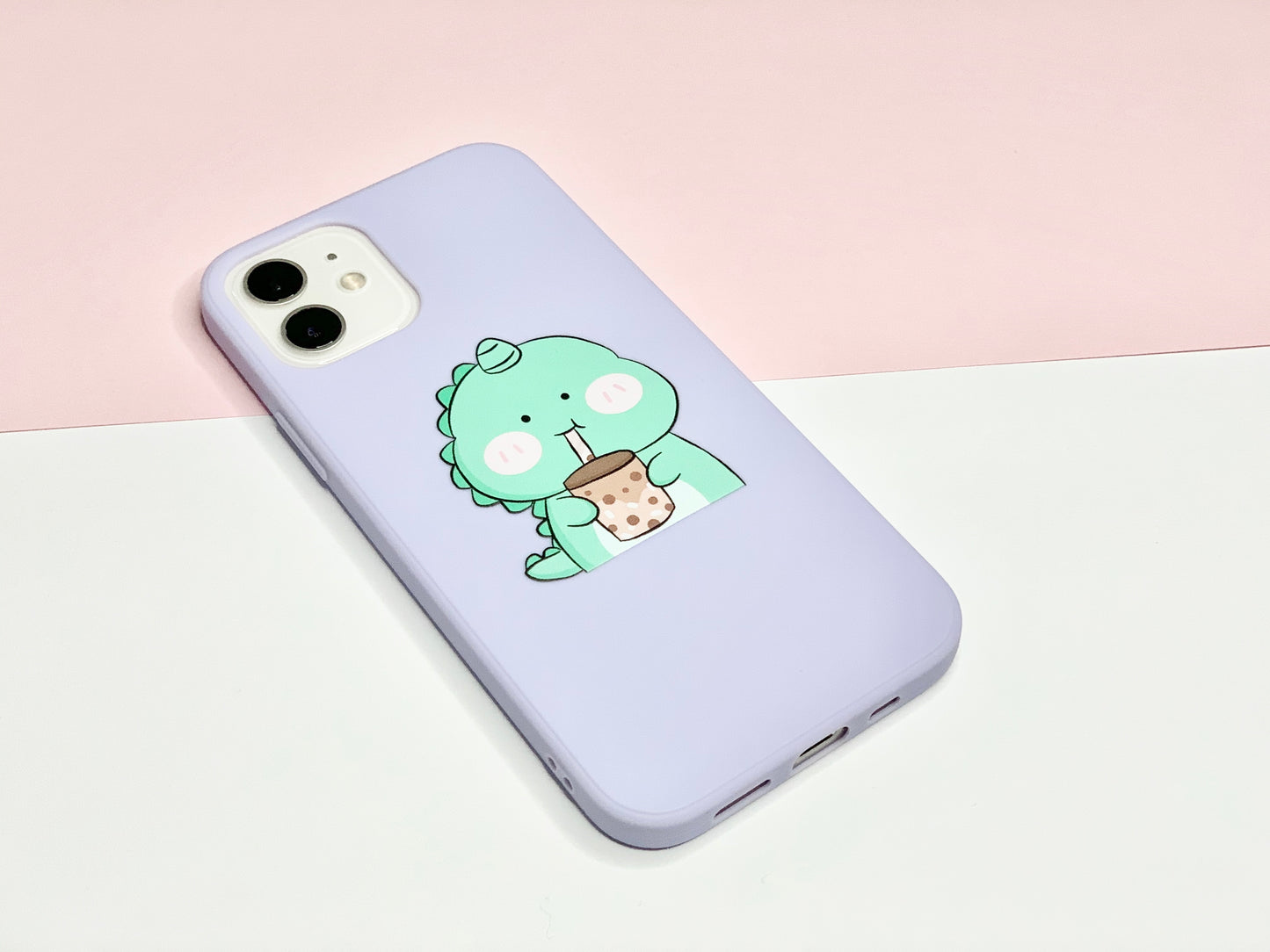 Coral and Ink's purple iPhone case is shown from a side angle. The case has a green dinosaur on it that is drinking Boba from a straw