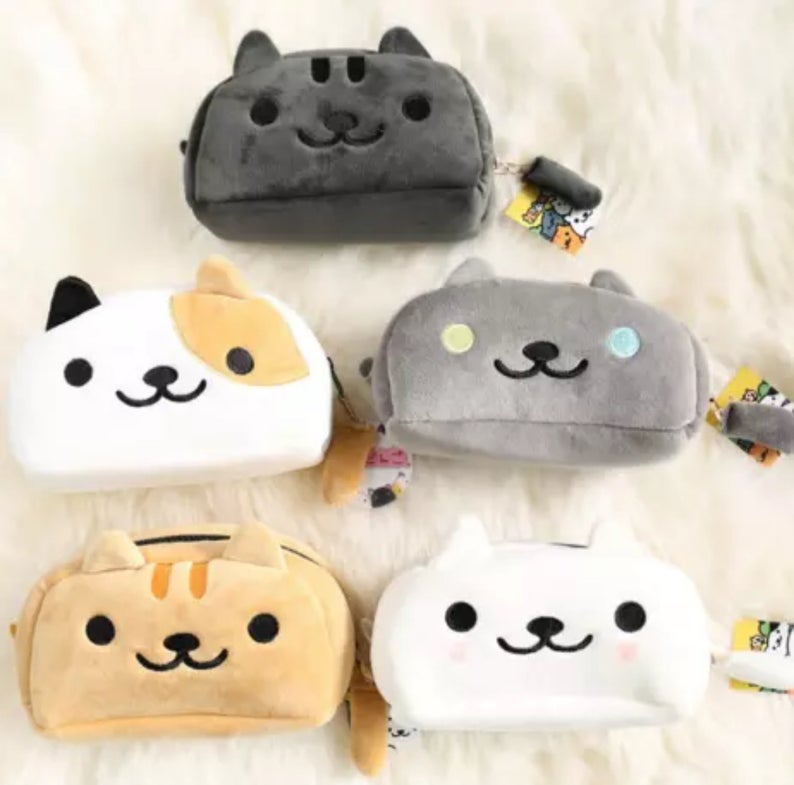 all 5 styles of coral and ink's cat plush pencil cases. There is a ginger cat, a white cat, a calico cat, a grey cat and a black cat